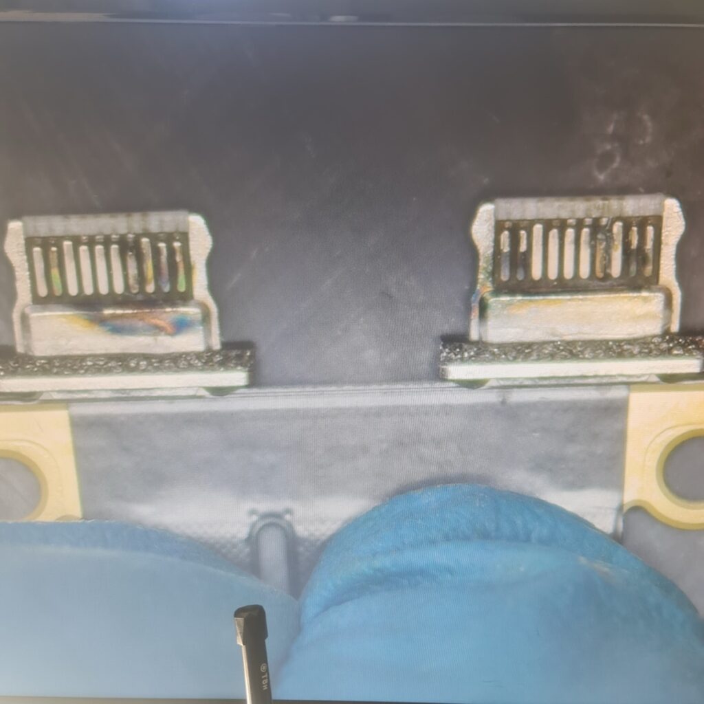 Microscopic view showing green oxidation and corrosion on the internal pins of a MacBook Air USB-C connector caused by liquid ingress.